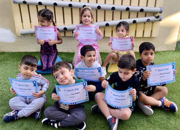 Nursery school students showing off their Sports Day certificates