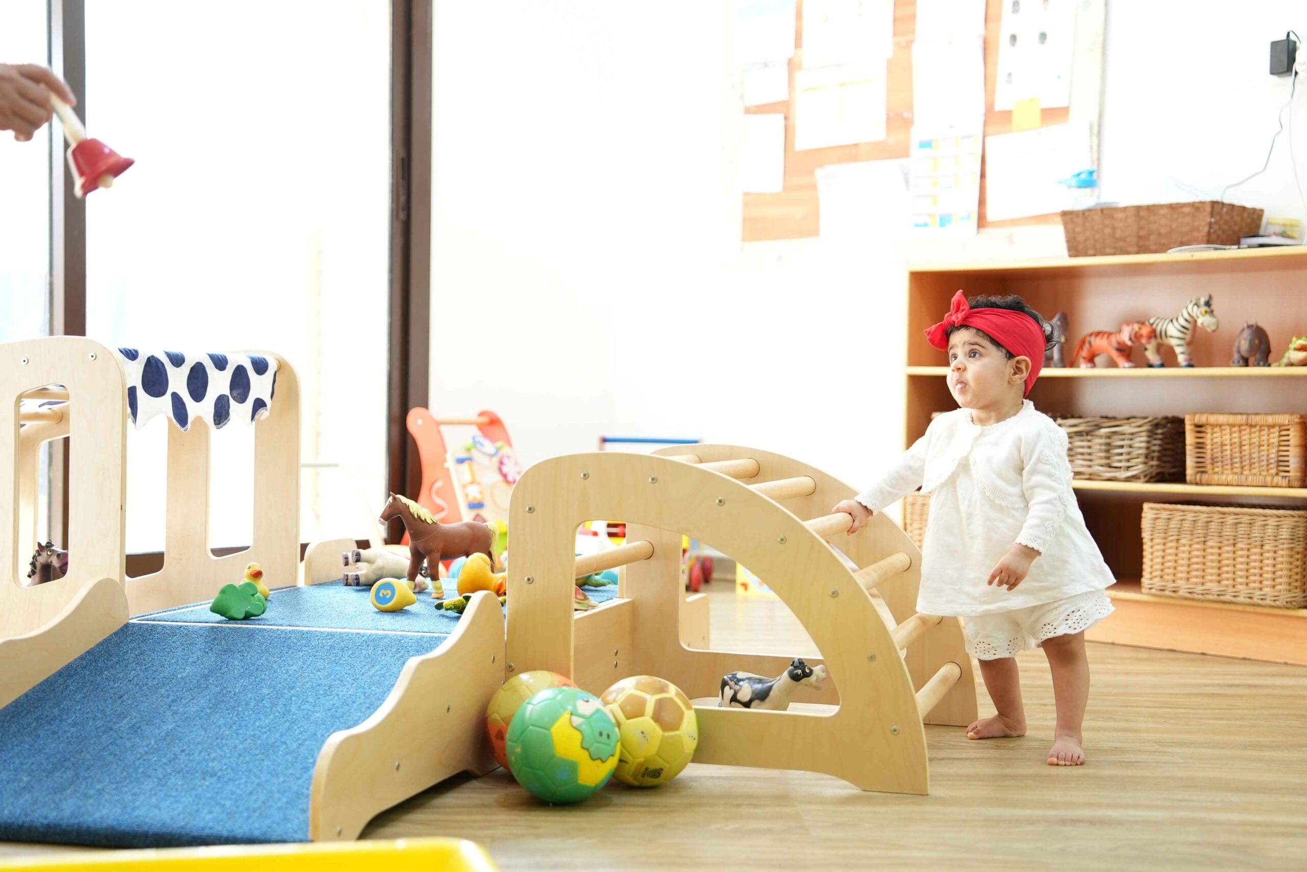 Two babies exploring toys on a play mat alongside a Step by Step educator