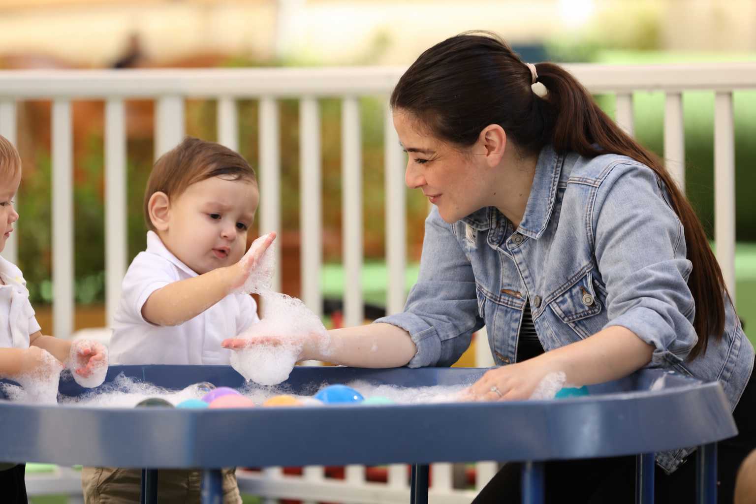 Step by Step Nursery team member holding a baby during an outdoor Baby & Me experience